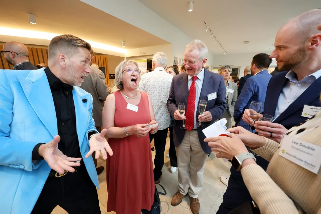 Guests laughing as Martin Sanderson performs close-up magic at a corporate drinks reception