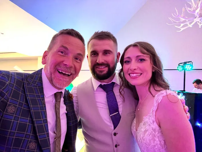 A newly married couple posing for a selfie with Martin Sanderson