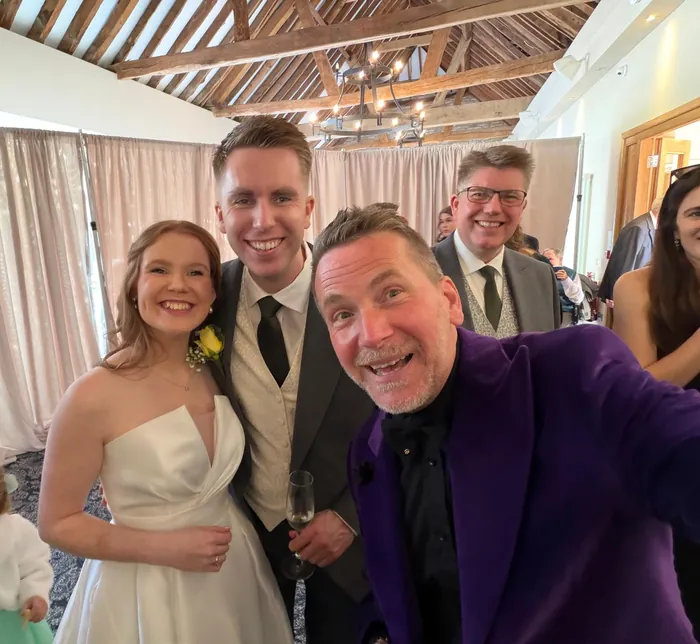 Newlyweds posing with Martin Sanderson at their wedding breakfast