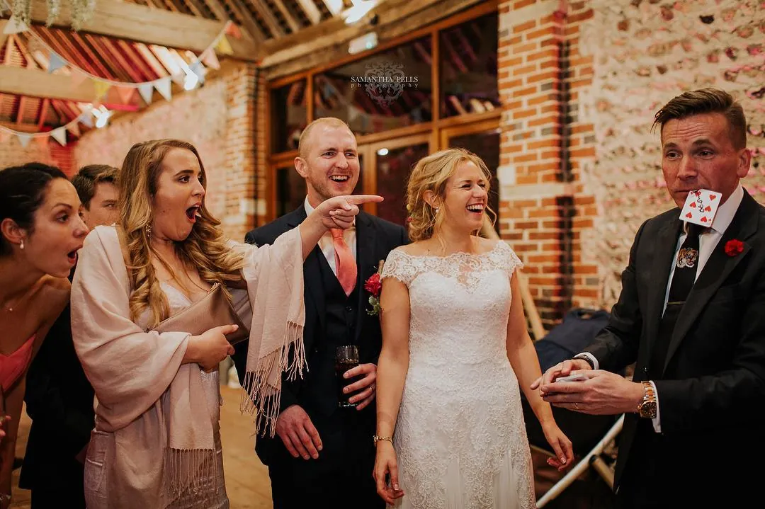 Wedding guests laughing during reception drinks as Martin Sanderson performs close-up magic